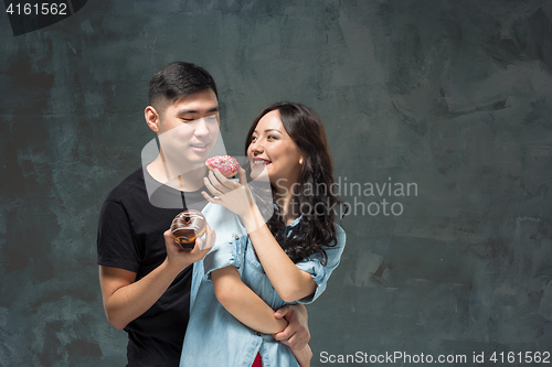 Image of Young asian couple enjoy eating of sweet colorful donut