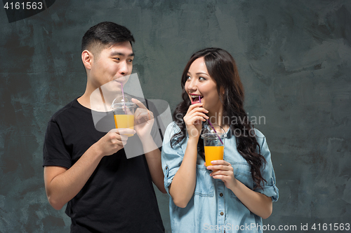 Image of young pretty Asian couple with  glasses of Orange juice