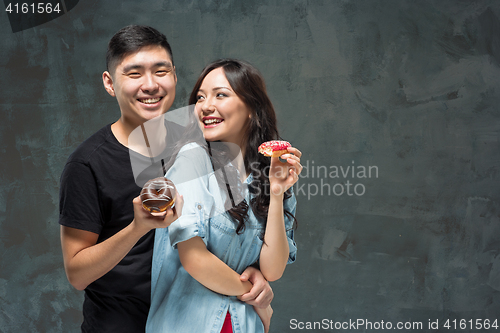 Image of Young asian couple enjoy eating of sweet colorful donut