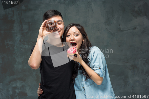 Image of Young asian couple enjoy eating of sweet colorful donut