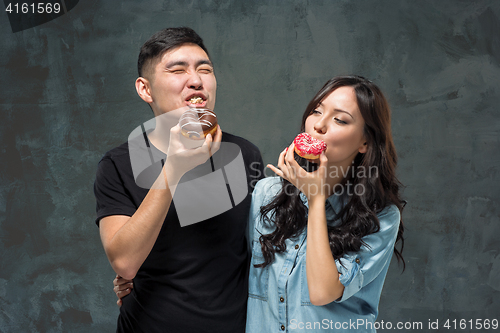 Image of Young asian couple enjoy eating of sweet colorful donut