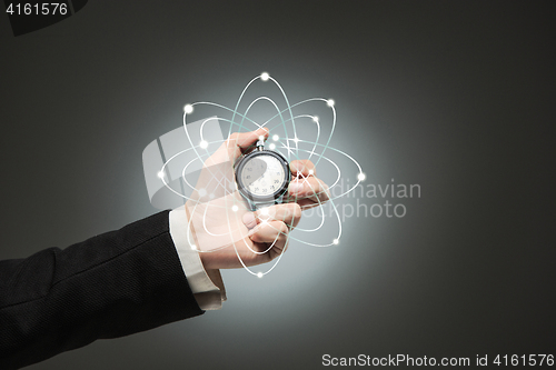 Image of hand holding a stopwatch against  white background