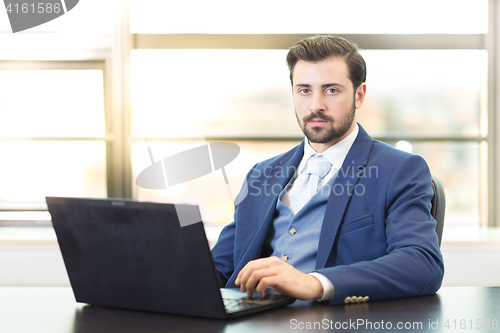 Image of Businessman in office working on laptop computer.