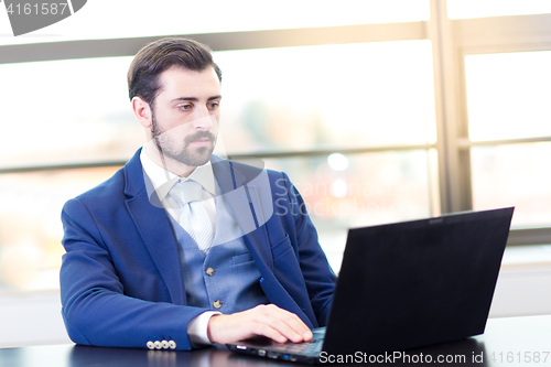 Image of Businessman in office working on laptop computer.