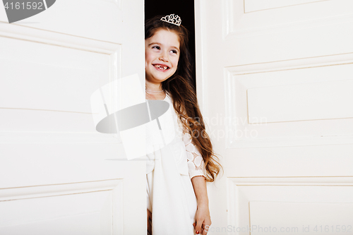 Image of little cute girl at home, opening door well-dressed in white dre