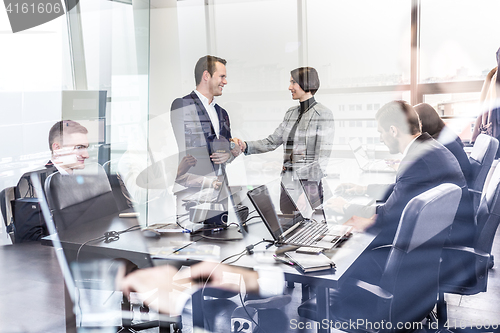 Image of Business people shaking hands in moder corporate office.