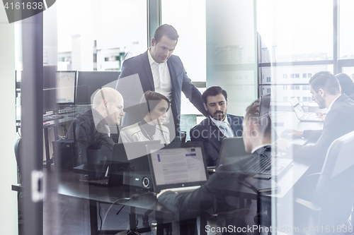 Image of Business team working in corporate office seen trougt glass door.