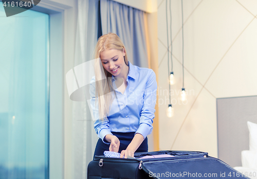 Image of businesswoman packing things in suitcase