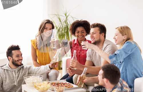 Image of happy friends with drinks having party at home