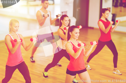 Image of group of smiling people working out with dumbbells