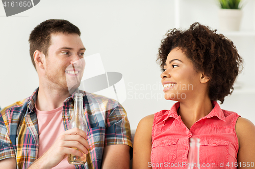 Image of happy friends or couple with beer talking at home