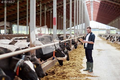 Image of man with clipboard and cows at dairy farm cowshed