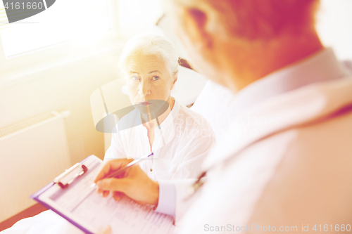 Image of senior woman and doctor with clipboard at hospital