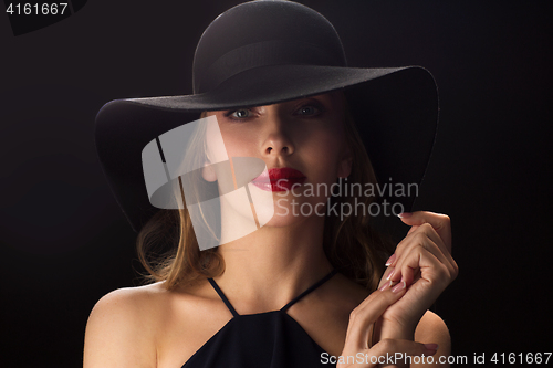 Image of beautiful woman in black hat over dark background