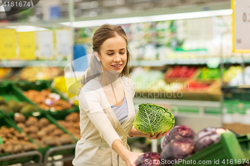 Image of happy woman buying savoy at grocery store