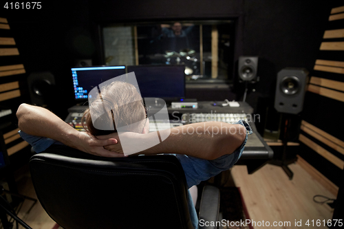 Image of man at mixing console in music recording studio