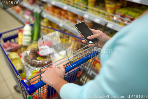 Image of woman with smartphone buying food at supermarket