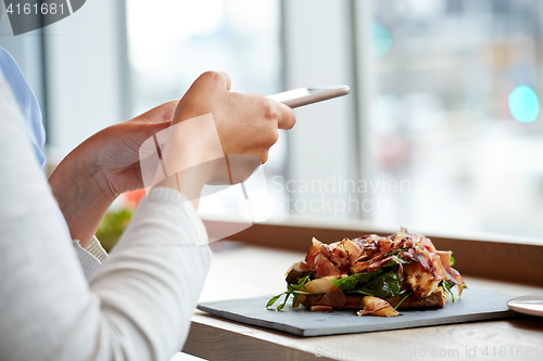 Image of woman with smartphone and ham salad at restaurant