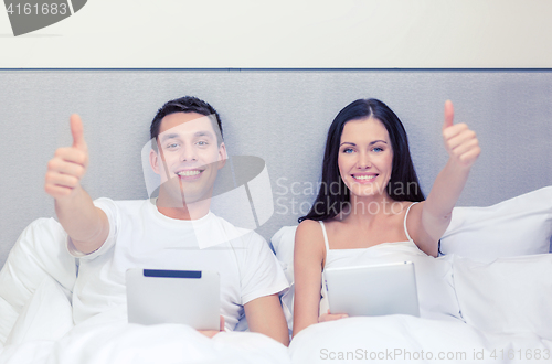 Image of smiling couple in bed with tablet pc computers