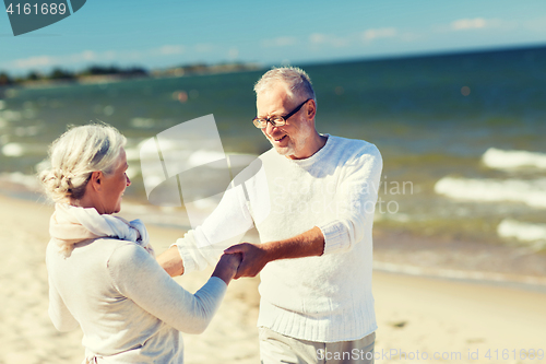 Image of happy senior couple holding hands on summer beach