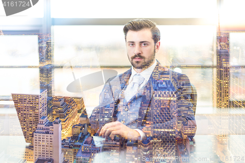 Image of Businessman in office working on laptop computer.