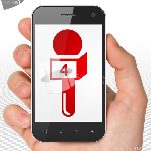 Image of News concept: Hand Holding Smartphone with Microphone on display