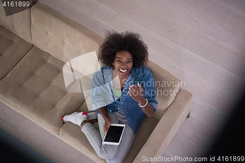 Image of african american woman at home with digital tablet top view