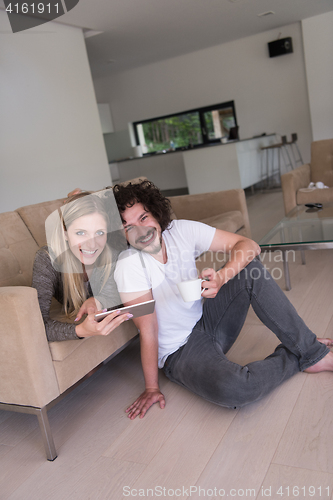 Image of couple relaxing at  home with tablet computers