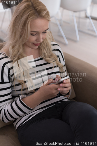 Image of woman sitting on sofa with mobile phone