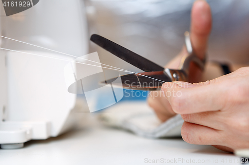 Image of Woman cuts thread with scissors