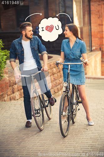 Image of Young couple sitting on a bicycle opposite city 