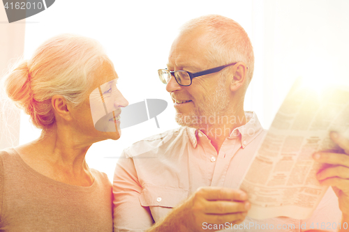 Image of happy senior couple reading newspaper at home