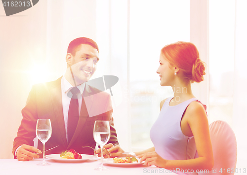 Image of smiling couple eating main course at restaurant