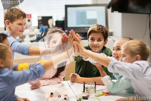 Image of happy children making high five at robotics school