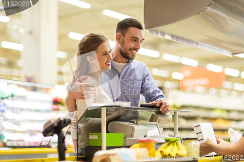 Image of couple buying food at grocery store cash register