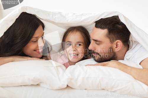 Image of happy family lying in bed under blanket at home