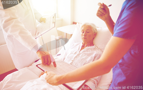 Image of doctor and nurse visiting senior woman at hospital