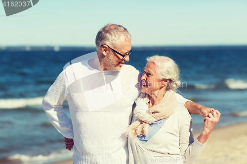 Image of happy senior couple hugging on summer beach