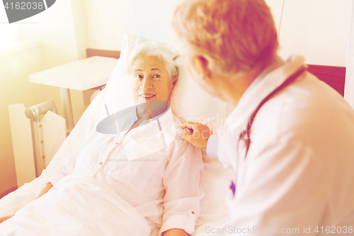 Image of doctor visiting senior woman at hospital ward