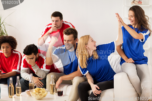 Image of friends or football fans watching soccer at home