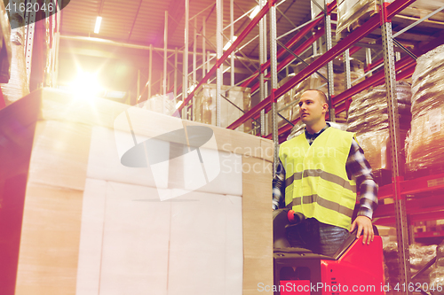 Image of man with tablet pc operating forklift at warehouse