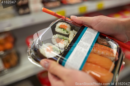 Image of hands with sushi pack at grocery or supermarket