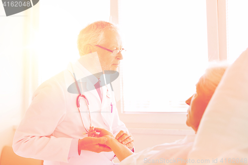 Image of doctor checking senior woman pulse at hospital