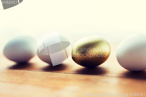 Image of close up of golden and white easter eggs on wood