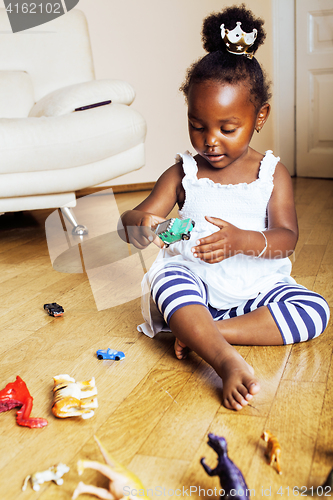 Image of little cute african american girl playing with animal toys at ho