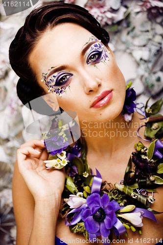 Image of floral face art with anemone in jewelry, sensual young brunette 