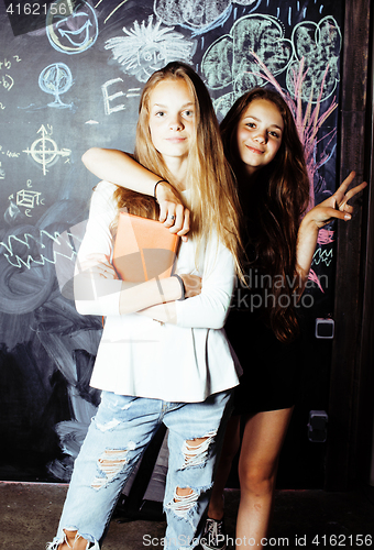 Image of back to school after summer vacations, two teen real girls in classroom with blackboard painted together