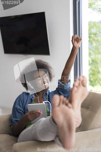 Image of African american woman at home in chair with tablet and head pho