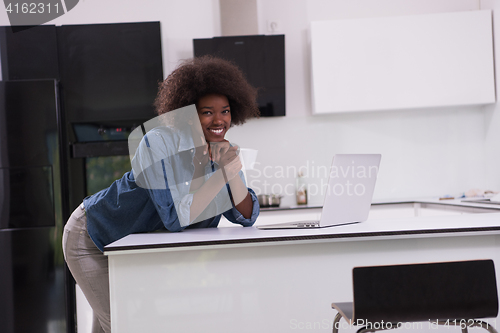 Image of smiling black woman in modern kitchen