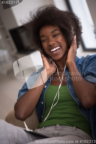 Image of African american woman at home in chair with tablet and head pho